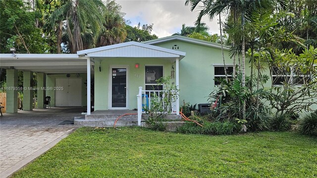 view of front of home with covered porch, a carport, and a front yard