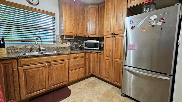 kitchen with sink, stainless steel appliances, tasteful backsplash, and dark stone counters