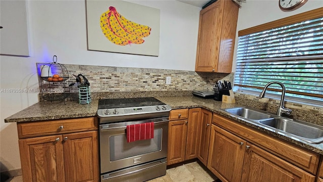 kitchen featuring dark stone countertops, backsplash, stainless steel electric range, and sink