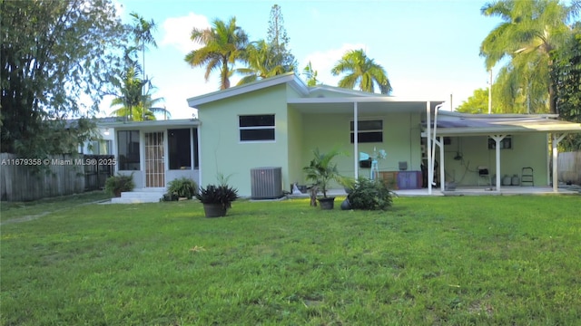 back of property featuring a lawn, a sunroom, a patio area, and central AC