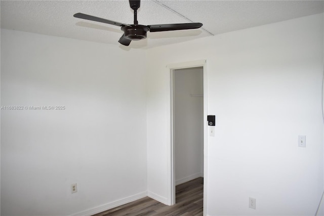 empty room with ceiling fan, dark wood-type flooring, and a textured ceiling