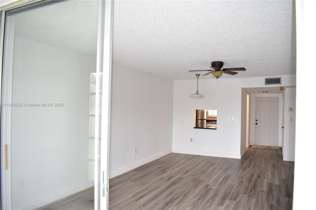 spare room featuring light wood-type flooring, a textured ceiling, and ceiling fan