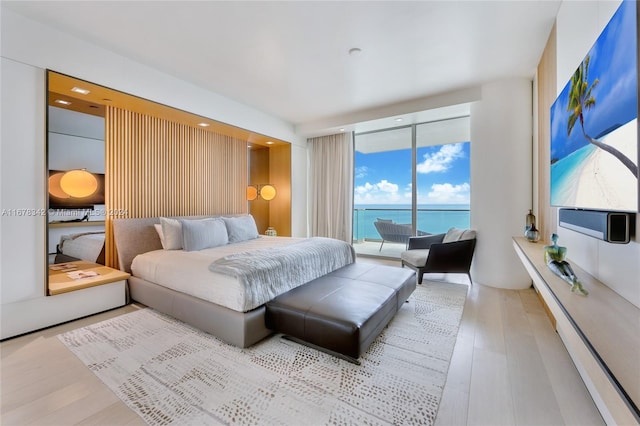 bedroom featuring access to exterior, light wood-type flooring, and floor to ceiling windows