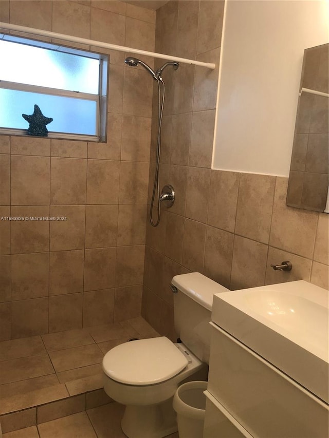 bathroom featuring tile patterned floors, toilet, vanity, tile walls, and a tile shower