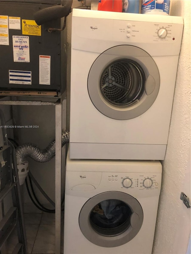 laundry room featuring stacked washing maching and dryer and tile patterned floors