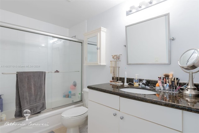 full bathroom with vanity, bath / shower combo with glass door, and toilet