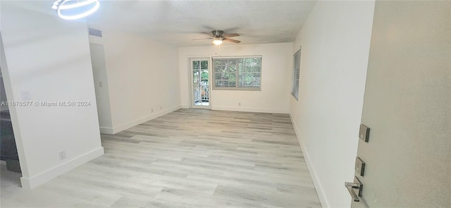 empty room featuring a textured ceiling, light wood-type flooring, and ceiling fan