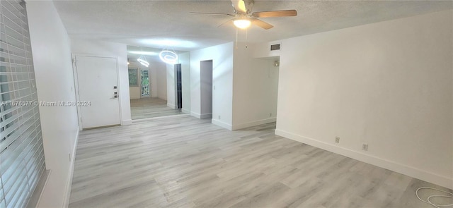 spare room featuring a textured ceiling, light wood-type flooring, and ceiling fan