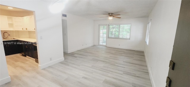 living room with light hardwood / wood-style floors, sink, and ceiling fan