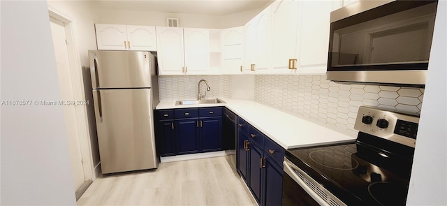 kitchen with sink, light hardwood / wood-style floors, stainless steel appliances, white cabinets, and blue cabinetry