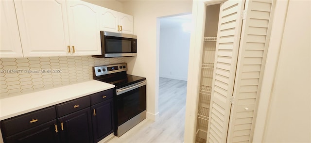 kitchen featuring light hardwood / wood-style floors, tasteful backsplash, appliances with stainless steel finishes, and white cabinets