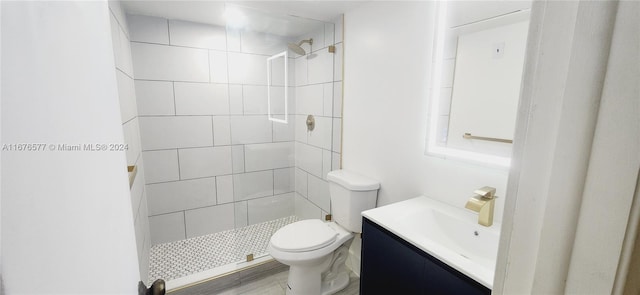 bathroom with vanity, toilet, a tile shower, and wood-type flooring