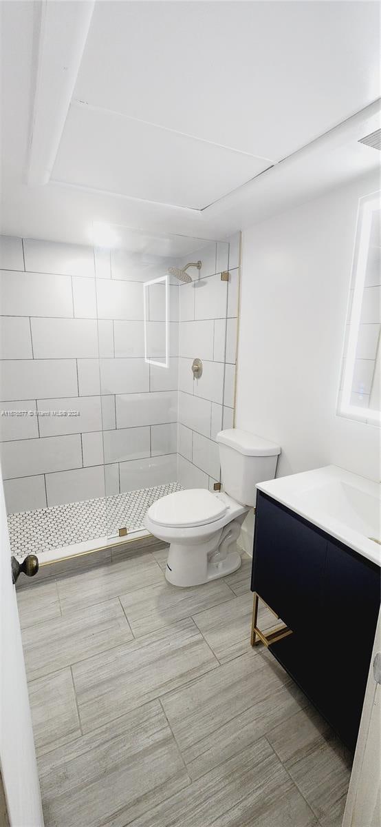 bathroom featuring vanity, tiled shower, and toilet