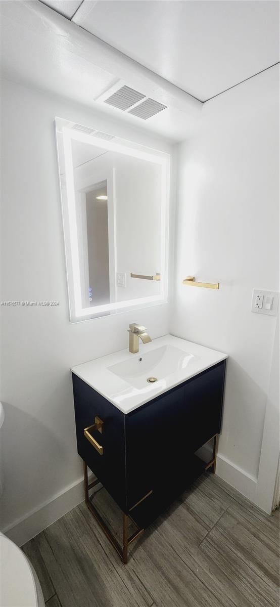 bathroom with vanity, toilet, and hardwood / wood-style flooring