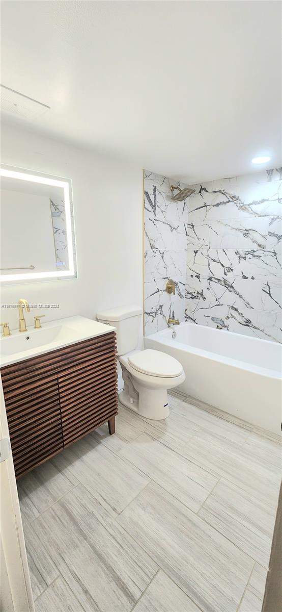 full bathroom with toilet, shower / bathing tub combination, vanity, and tile walls