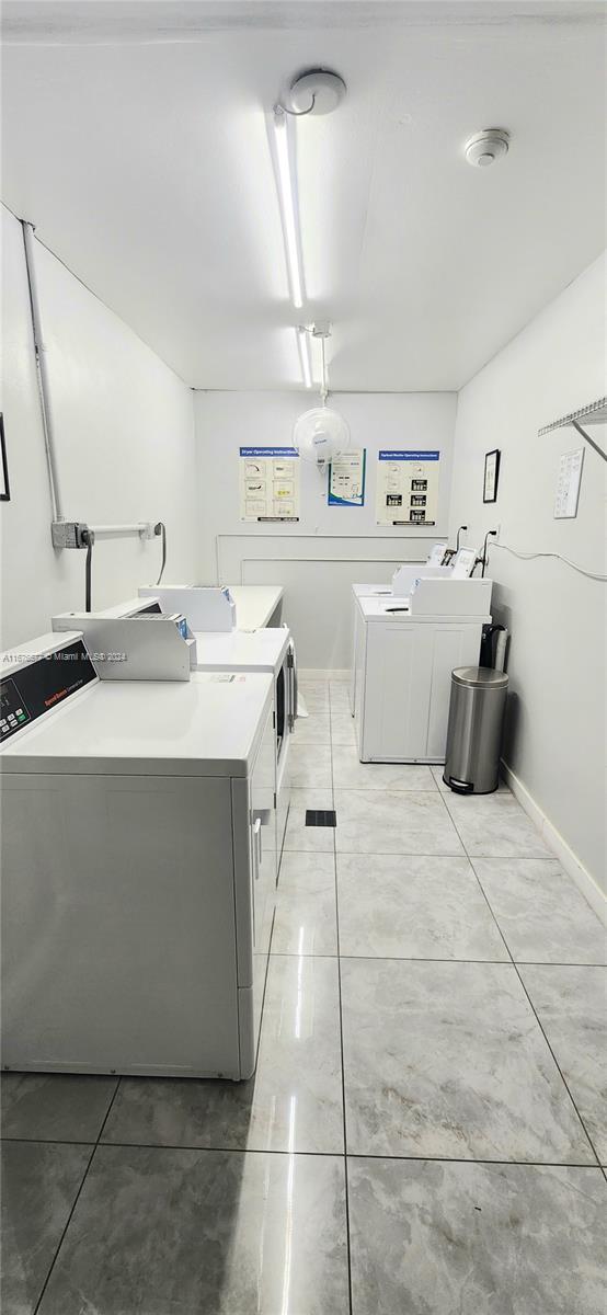 laundry room featuring washing machine and clothes dryer and light tile patterned floors