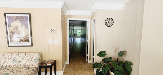 hallway featuring ornamental molding, light tile patterned flooring, a textured ceiling, and wood walls