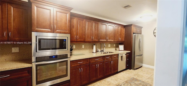 kitchen featuring backsplash, stainless steel appliances, light stone countertops, and sink