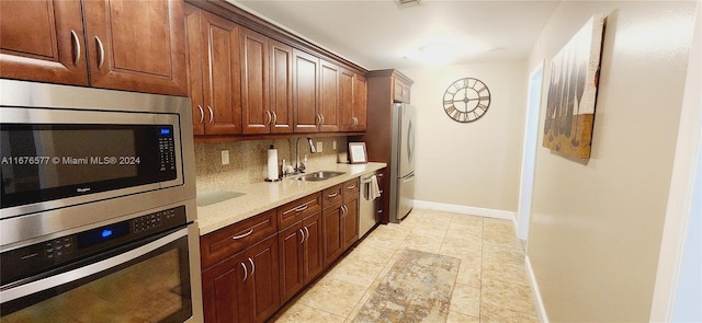 kitchen with decorative backsplash, light stone counters, light tile patterned floors, appliances with stainless steel finishes, and sink