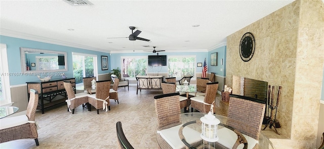 tiled dining area featuring tile walls, ornamental molding, a fireplace, and ceiling fan