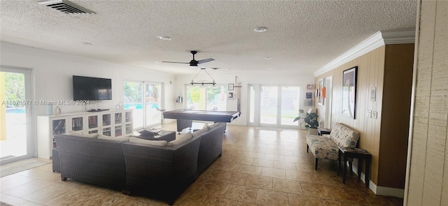 tiled living room with ornamental molding, a textured ceiling, and ceiling fan