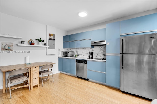 kitchen featuring tasteful backsplash, appliances with stainless steel finishes, blue cabinets, light hardwood / wood-style floors, and extractor fan