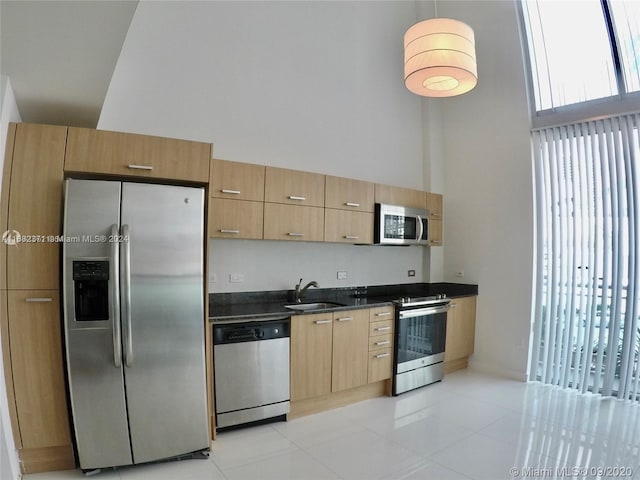 kitchen featuring light tile patterned floors, sink, appliances with stainless steel finishes, and a high ceiling