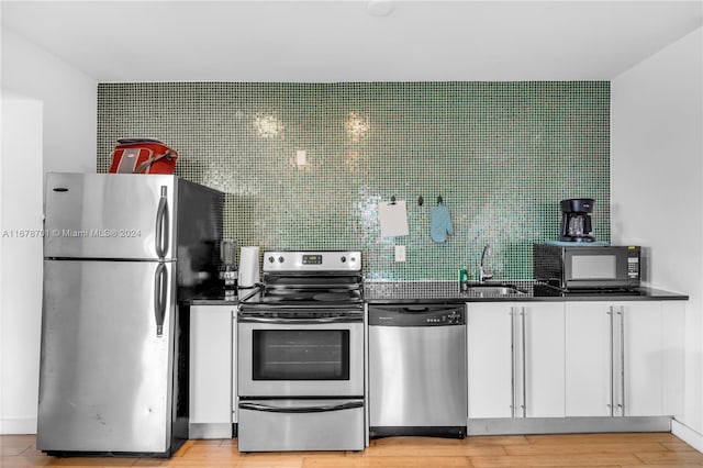 kitchen featuring tasteful backsplash, sink, white cabinetry, light hardwood / wood-style floors, and stainless steel appliances