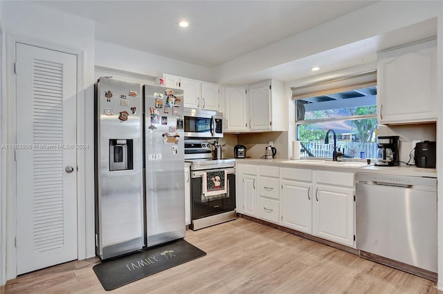 kitchen featuring white cabinets, light wood-type flooring, stainless steel appliances, and sink