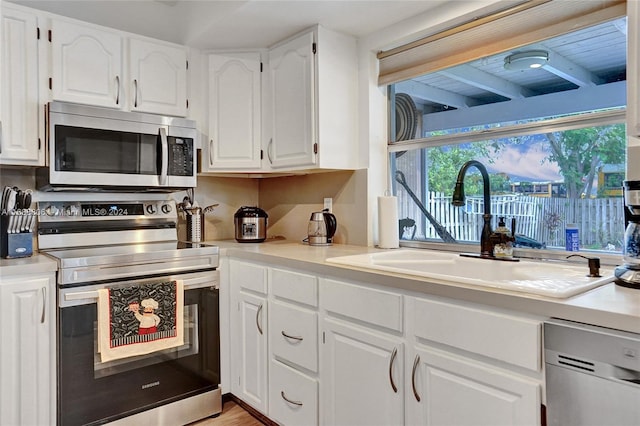 kitchen with white cabinetry, sink, light hardwood / wood-style flooring, and appliances with stainless steel finishes