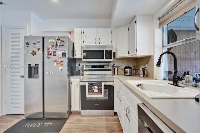 kitchen with white cabinets, light wood-type flooring, appliances with stainless steel finishes, and sink