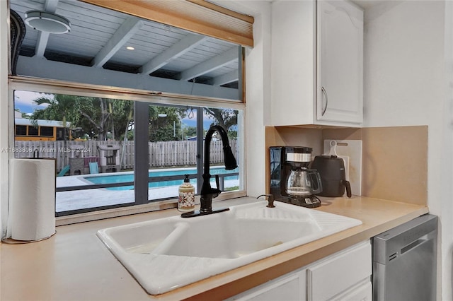 kitchen featuring sink, wooden ceiling, stainless steel dishwasher, beam ceiling, and white cabinetry