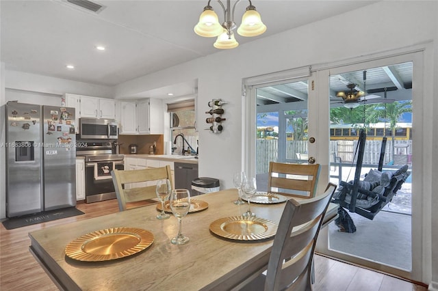 dining room with an inviting chandelier, sink, and light hardwood / wood-style flooring