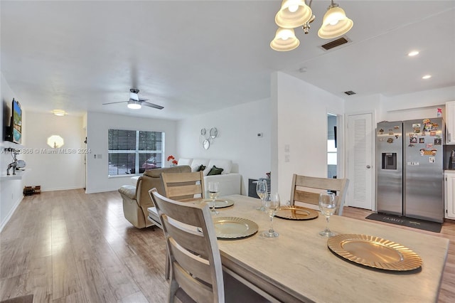 dining space featuring ceiling fan with notable chandelier and light hardwood / wood-style flooring