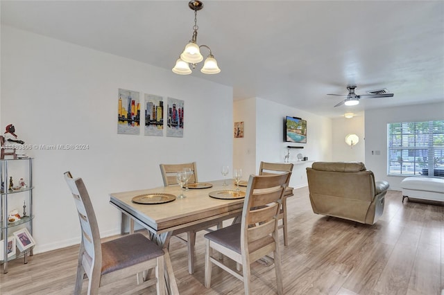 dining room featuring ceiling fan with notable chandelier and light hardwood / wood-style floors