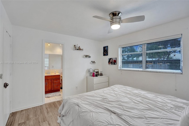 bedroom with light hardwood / wood-style flooring, ceiling fan, and ensuite bath