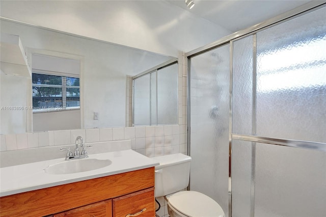 bathroom featuring walk in shower, toilet, vanity, and tasteful backsplash