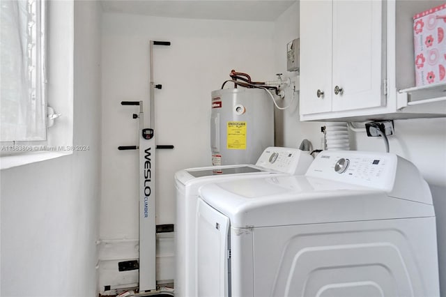 laundry room featuring water heater, washing machine and dryer, and cabinets