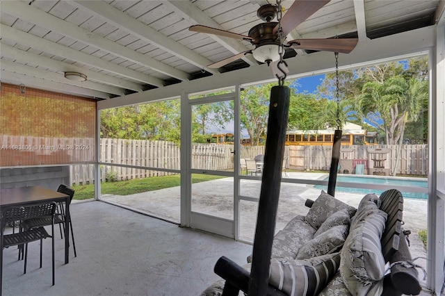 sunroom with ceiling fan and beam ceiling