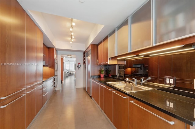 kitchen featuring sink, dark stone countertops, stainless steel appliances, and rail lighting