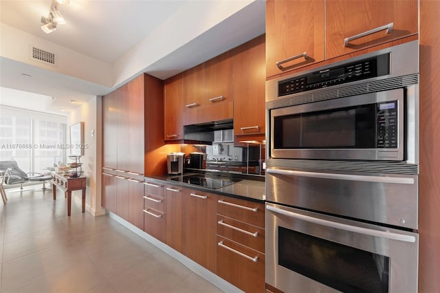 kitchen featuring dark stone countertops, double oven, and black electric cooktop