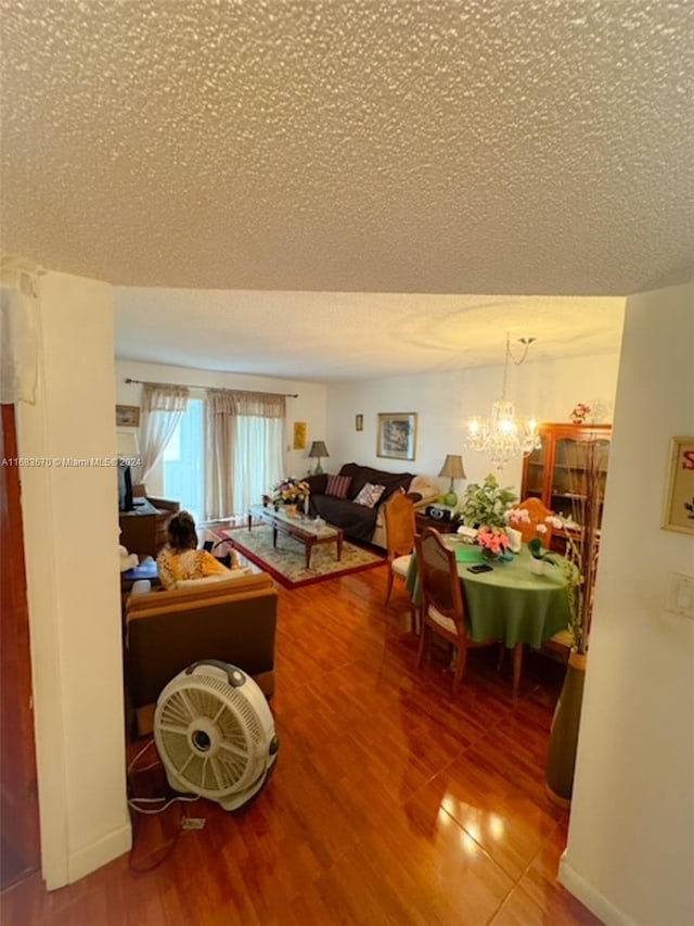 living room with a notable chandelier, a textured ceiling, and hardwood / wood-style flooring