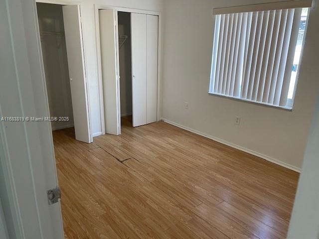 unfurnished bedroom featuring two closets and light wood-type flooring