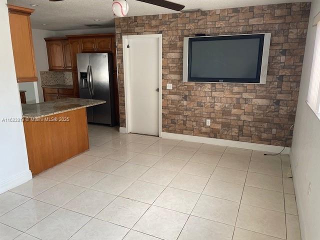 kitchen featuring light tile patterned floors, a textured ceiling, stainless steel fridge, and ceiling fan