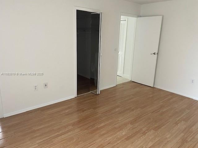 unfurnished bedroom with hardwood / wood-style floors, a spacious closet, and a closet