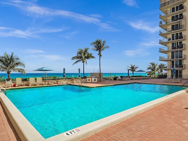 view of pool featuring a water view and a patio