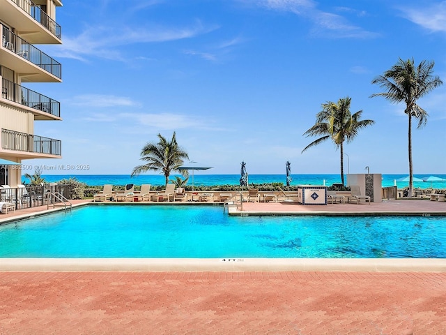 view of swimming pool featuring a patio and a water view