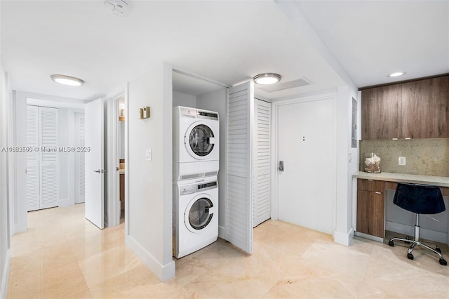 clothes washing area featuring stacked washing maching and dryer