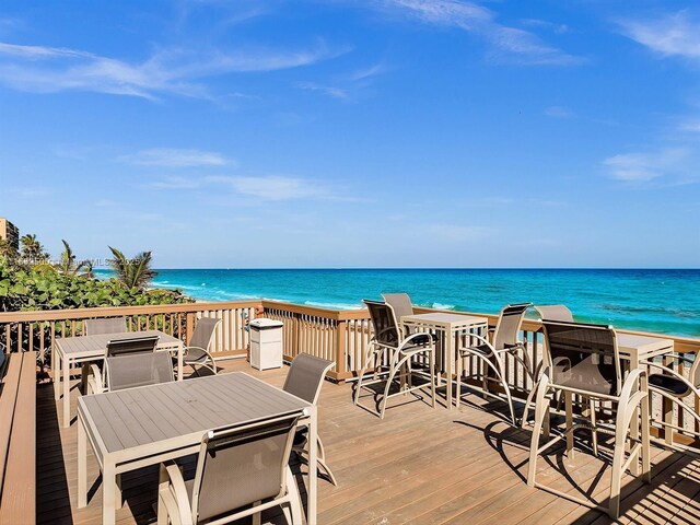 wooden terrace featuring a water view and a beach view