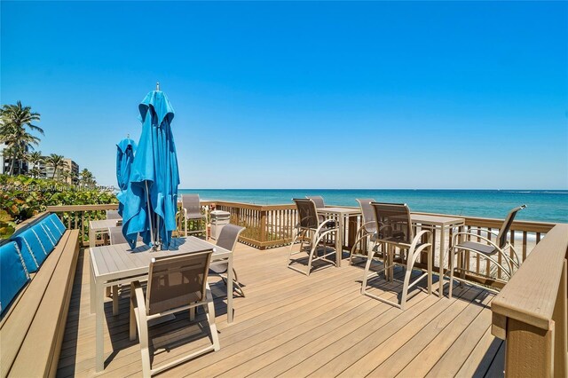 wooden terrace with a water view and a view of the beach